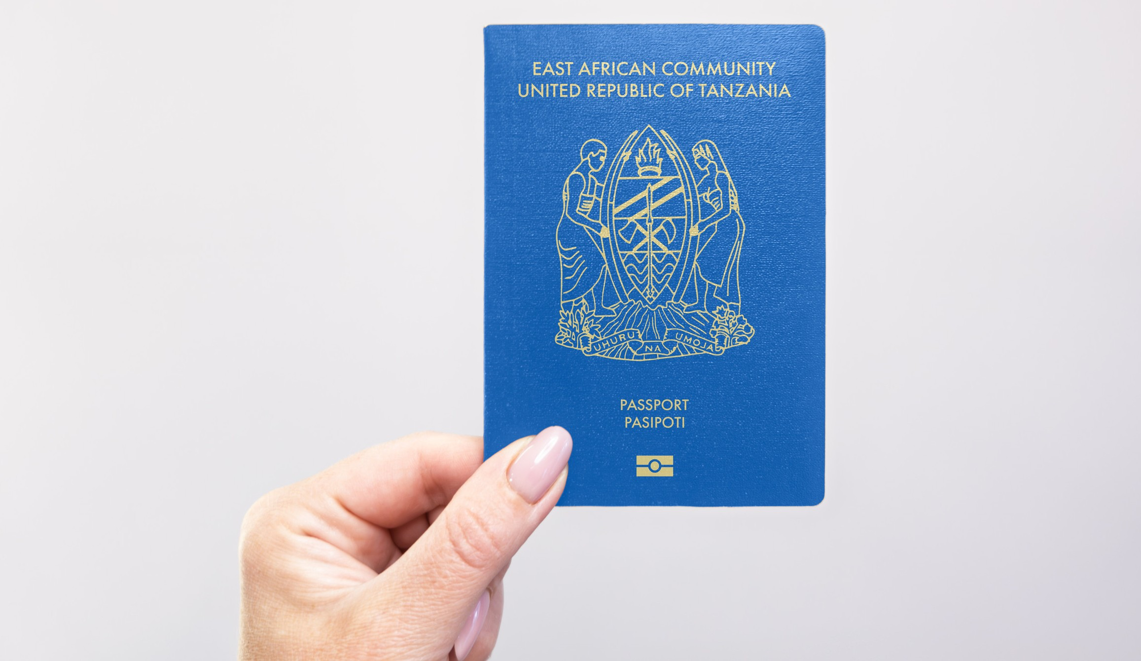 Close Up Of A Tanzania Passport Held In Hand Against A Plain White Background