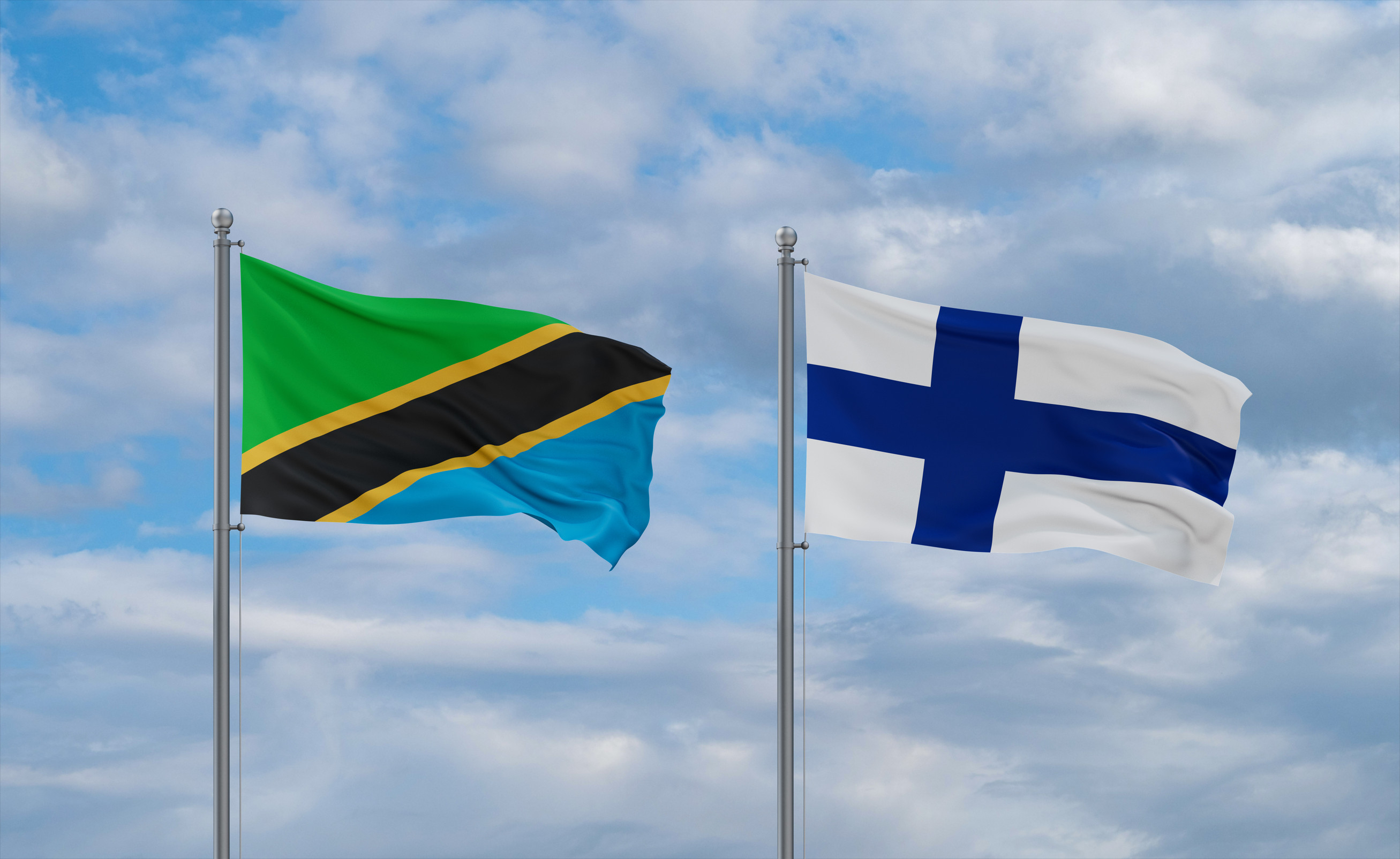 Finland And Tanzania Flags Waving Together On Blue Cloudy Sky