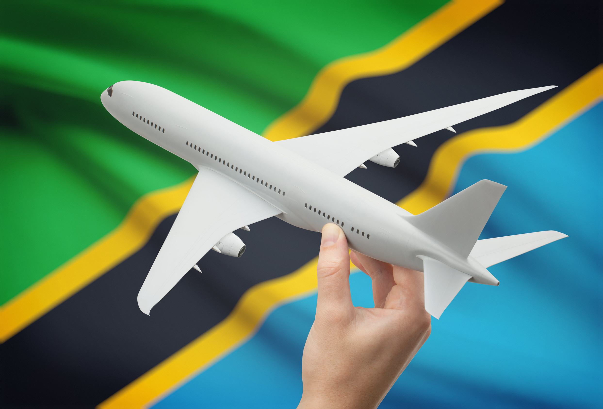Hand With A Plane In Front Of A Tanzania Flag