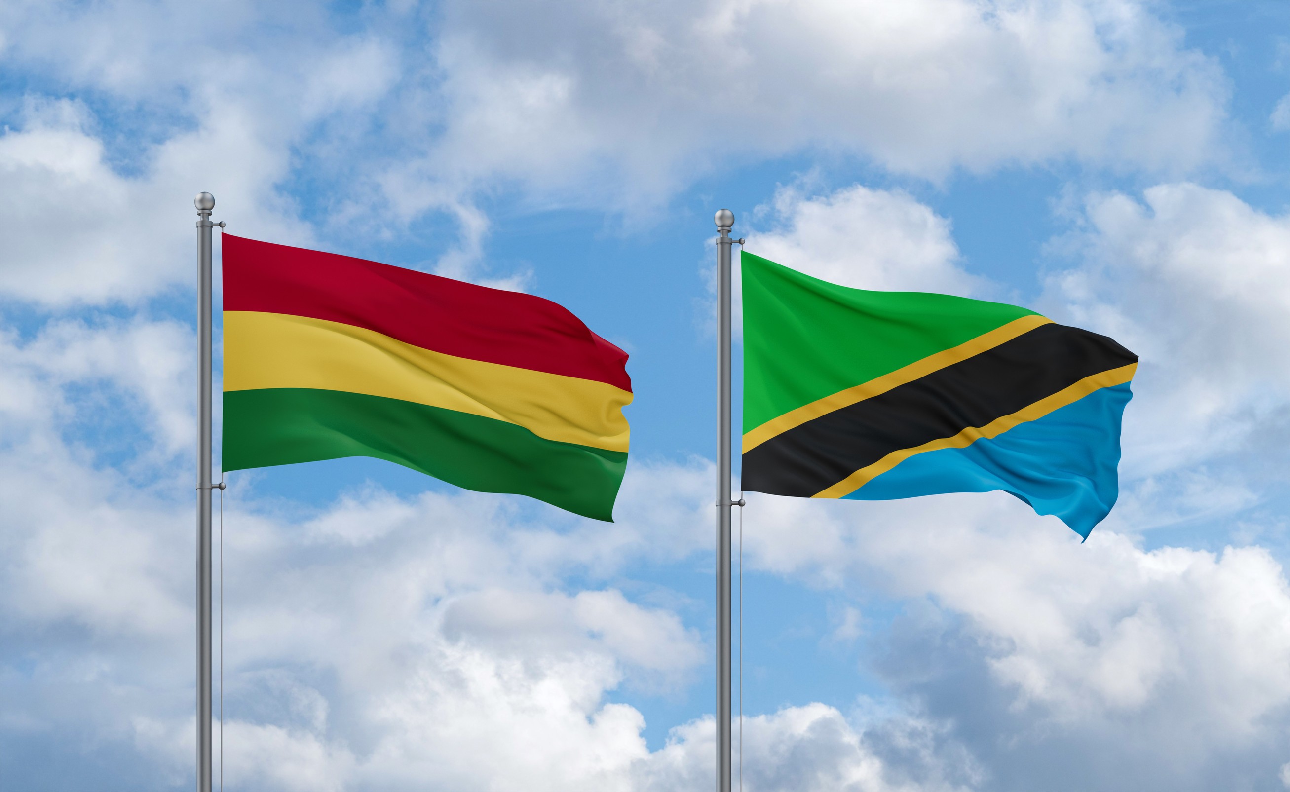 Tanzania And Bolivia Flags Waving Together In The Wind On Blue Cloudy Sky