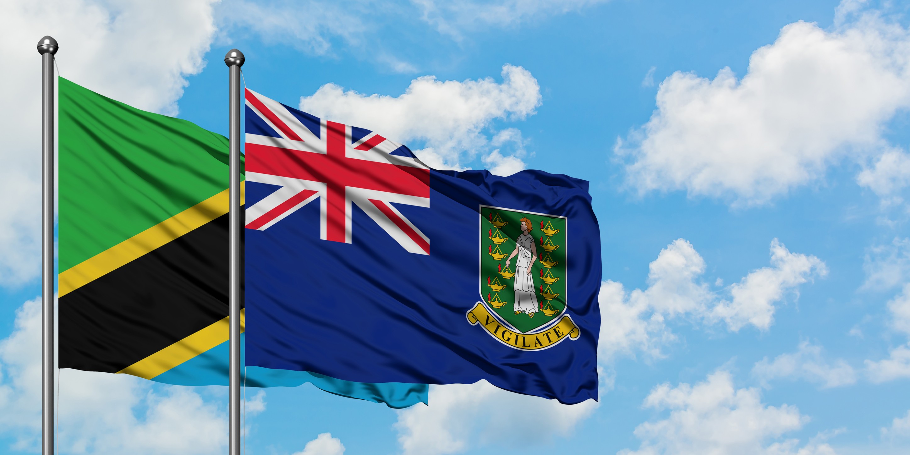 Tanzania And Cayman Islands Flags Flying Side By Side Against The Sky