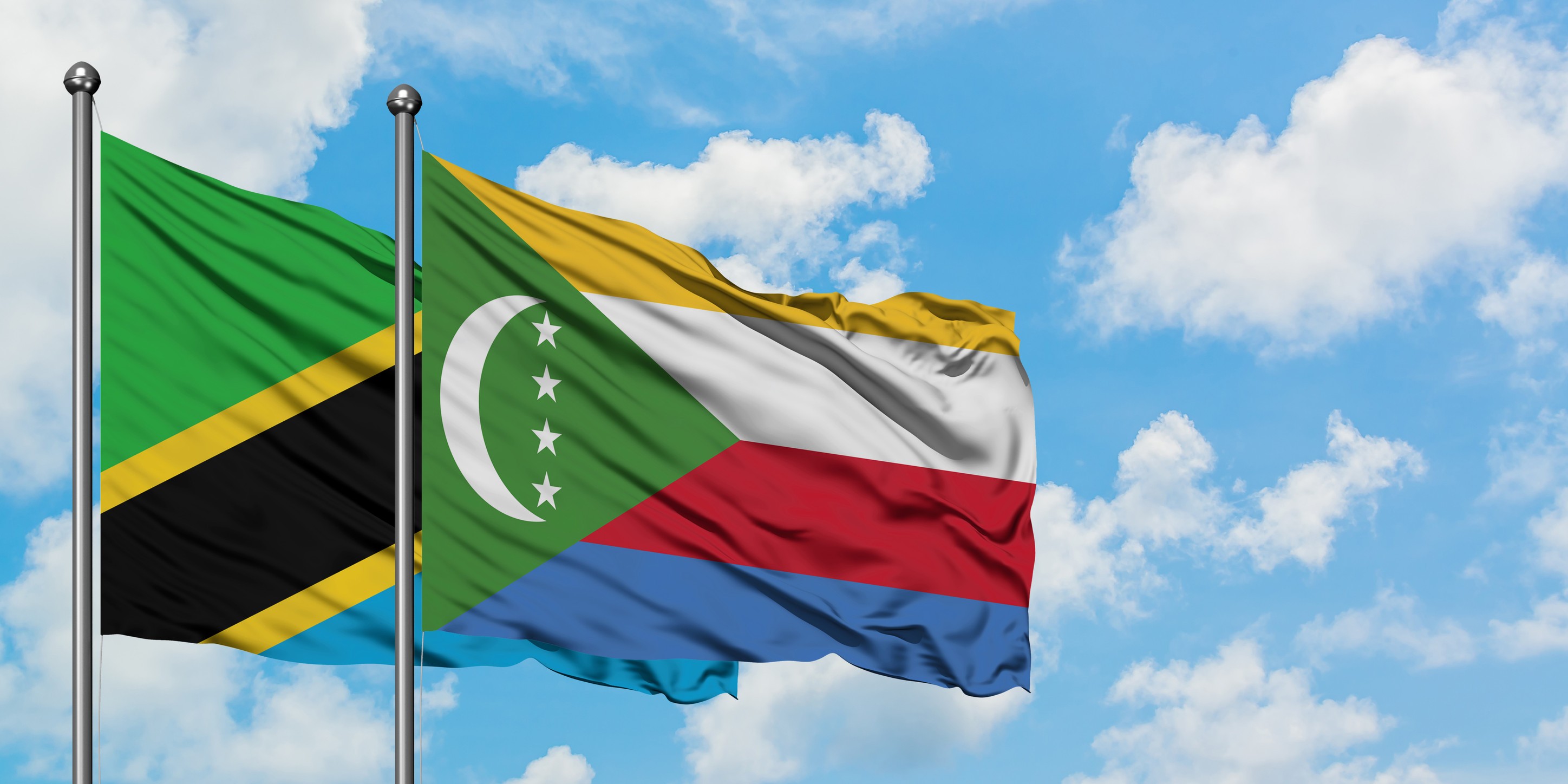 Tanzania And Comoros Flag Waving In The Wind Against White Cloudy