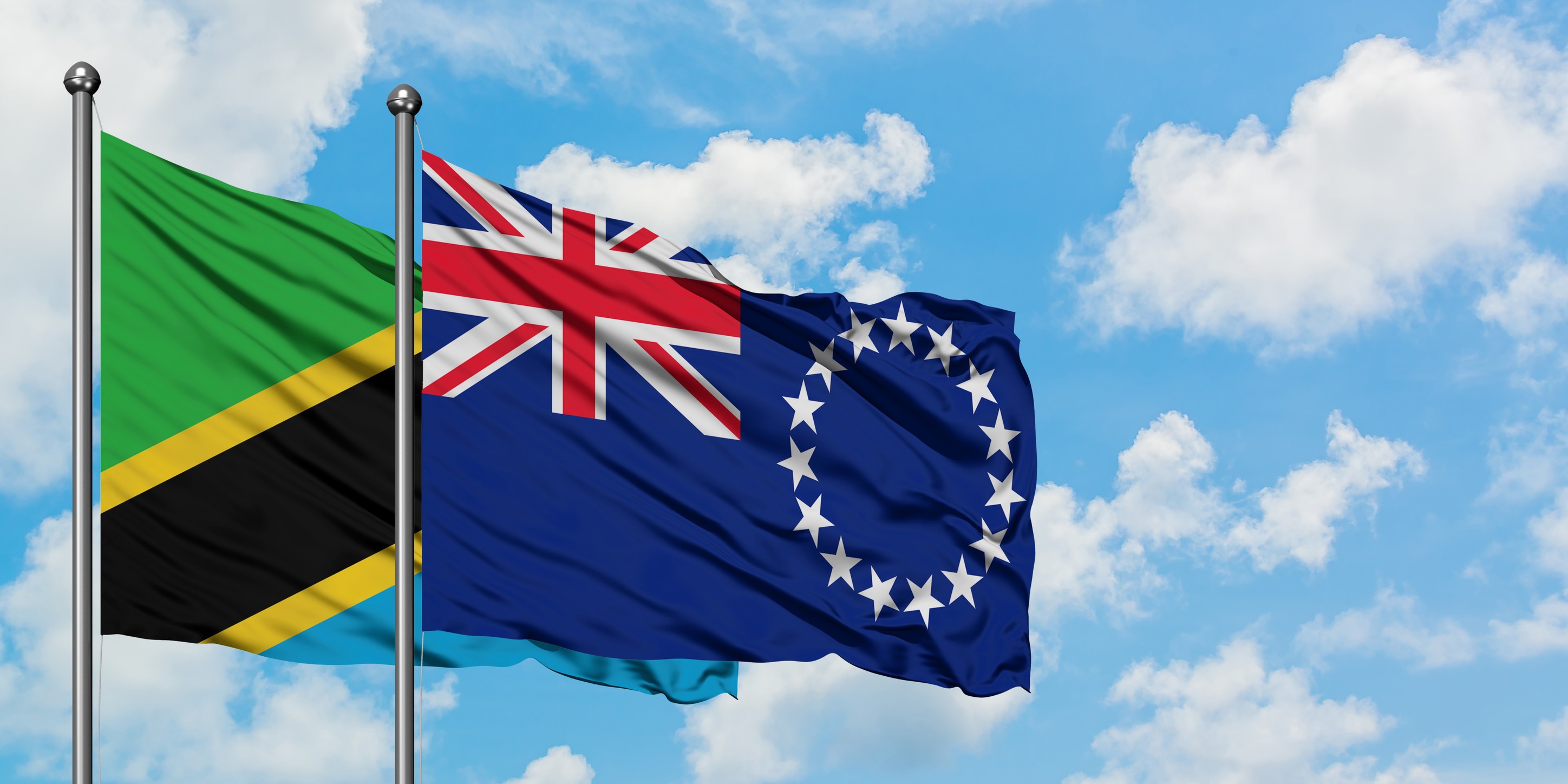 Tanzania And Cook Islands Flag Waving In The Wind Against White Cloudy