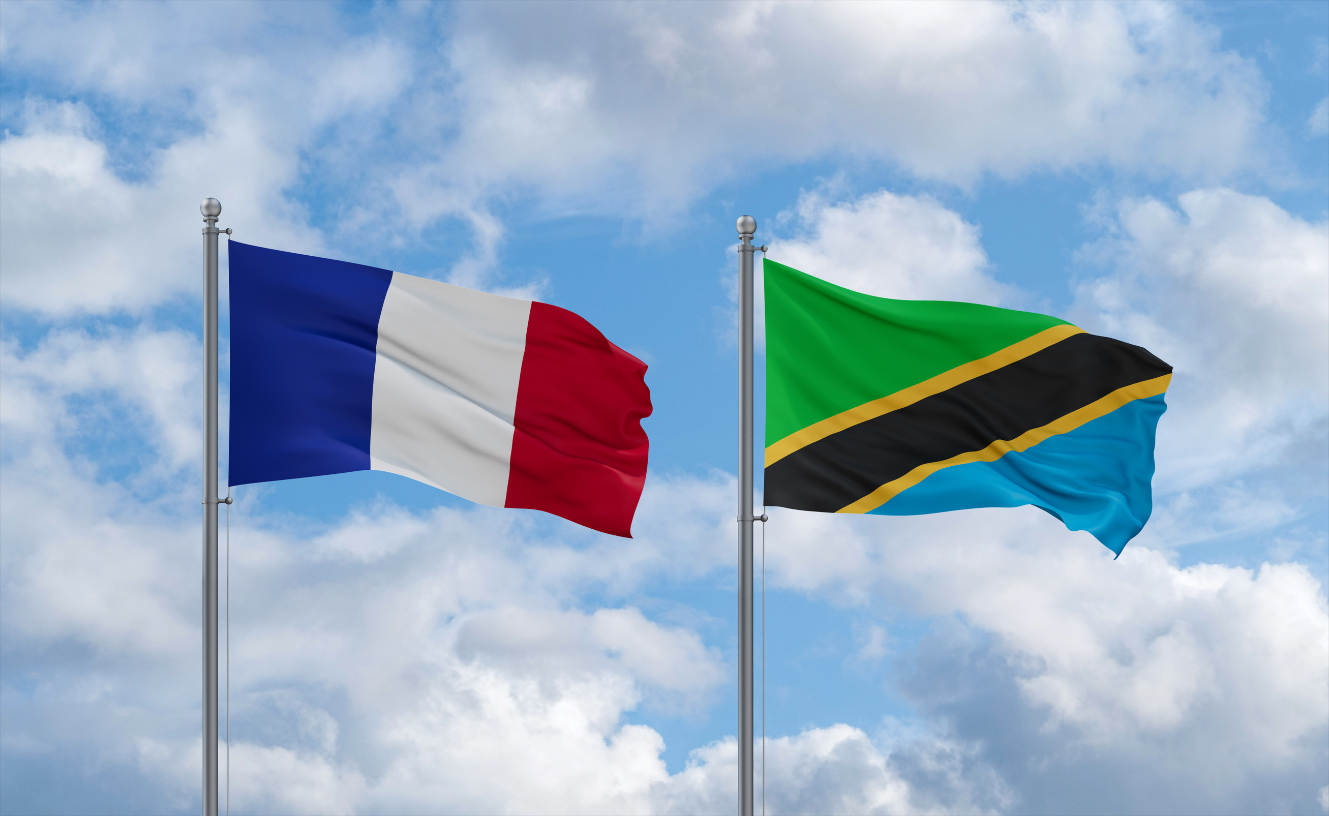 Tanzania And France Flags Waving Together In The Wind On Blue Cloudy